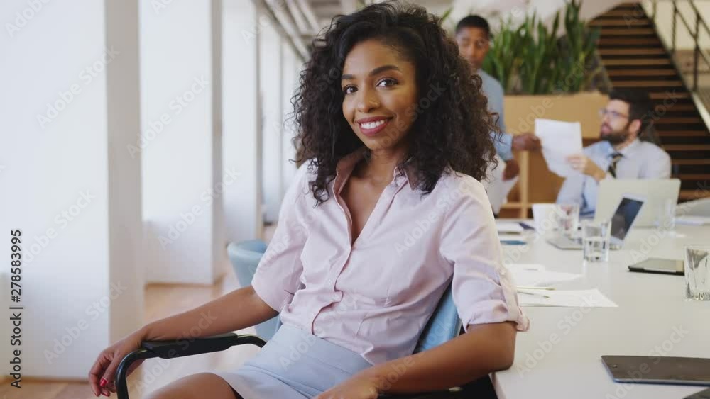 Wall mural portrait of businesswoman in modern office with colleagues meeting around table in background