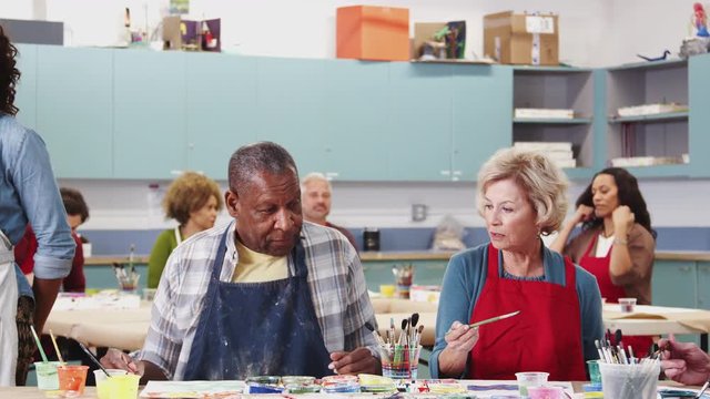 Group Of Retired Seniors Attending Art Class In Community Centre With Teacher