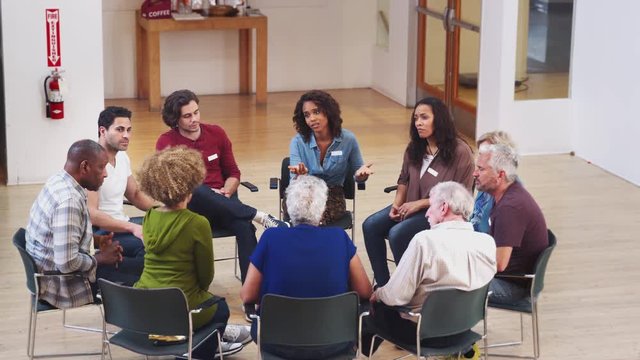 People Sitting In Circle Attending Self Help Therapy Group Meeting In Community Center