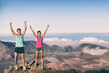 Hiking people goal achievement reaching summit mountain hikers. Man and woman on top of the world happy celebrating success. Female and male athletes cheering winning at Maui Volcano Haleakala Hawaii.