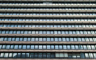 the facade of a office building with many windows arranged in a line,