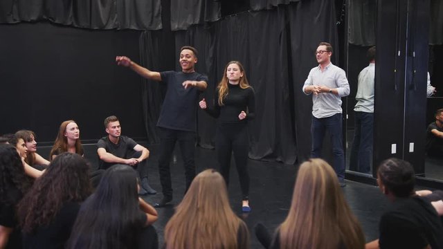 Teacher With Drama Students At Performing Arts School In Studio Improvisation Class