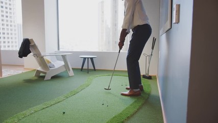 Businessman Practicing Golf On Indoor Putting Surface In Office - Powered by Adobe