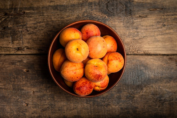 Delicious ripe apricots in a wooden bowl on the table close-up. Horizontal view from above