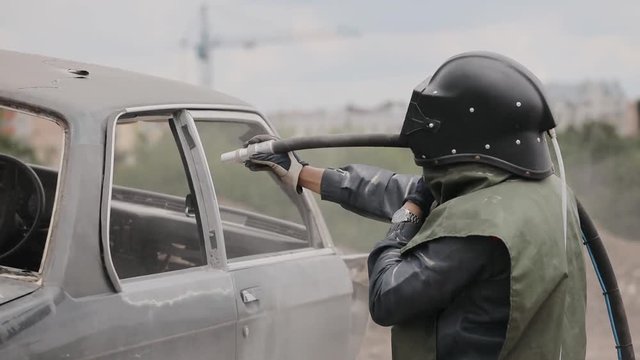 Sandblasting of metal surface of the car by compressed air of the sandblaster gun