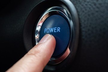 Hand push on car engine power start button close up