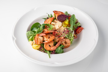 Luxurious seafood salad with grilled king prawns, fish, parmesan cheese, greens and vegetables. Banquet festive dishes. Fine dining restaurant menu. White background.