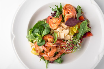 Luxurious seafood salad with grilled king prawns, fish, parmesan cheese, greens and vegetables. Banquet festive dishes. Fine dining restaurant menu. White background.