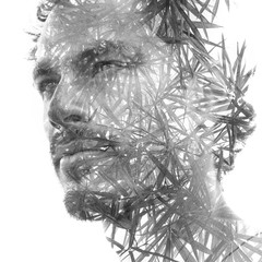 Double exposure of a young handsome man’s portrait blended with tropical leaves, showing the...