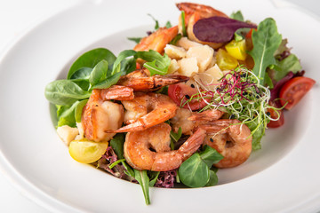 Luxurious seafood salad with grilled king prawns, fish, parmesan cheese, greens and vegetables. Banquet festive dishes. Fine dining restaurant menu. White background.