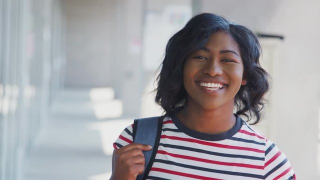 Portrait Of Smiling Female University Student With Backpack In Corridor Of College Building 