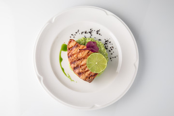 Grilled fish fillet salmon. Selected pieces of red fish with champagne and spinach risotto. Seafood. Banquet festive dishes. Fine dining restaurant menu. White background.