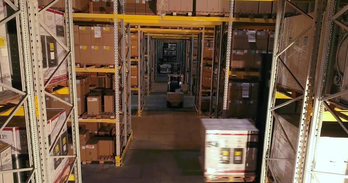 The forklift carries boxes with products at the warehouse, forklifts traveling between the rows in the warehouse. Industrial interior