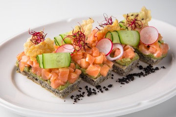 Bruschetta with salmon, avocado, capers, cucumber, radish, sweet pepper and cherry tomatoes. Banquet festive dishes. Fine dining restaurant menu. White background.