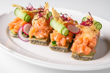 Bruschetta with salmon, avocado, capers, cucumber, radish, sweet pepper and cherry tomatoes. Banquet festive dishes. Fine dining restaurant menu. White background.