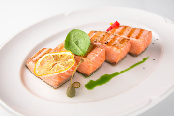 Grilled fish fillet salmon. Selected pieces of red fish. Seafood. Banquet festive dishes. Fine dining restaurant menu. White background.