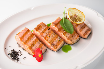 Grilled fish fillet salmon. Selected pieces of red fish. Seafood. Banquet festive dishes. Fine dining restaurant menu. White background.