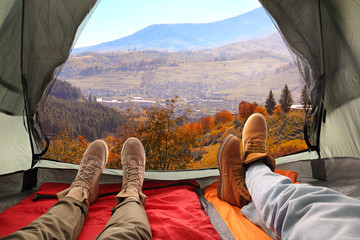 Closeup of people in camping tent with sleeping bags on mountain hill, view from inside - obrazy, fototapety, plakaty