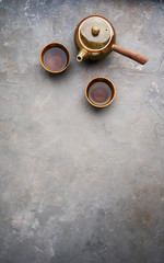 Traditional clay Japanese teapot kyusu with side handle for brewing green tea with two teacup on gray background with copy space. Flat lay.