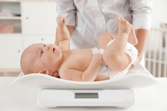 Doctor weighting baby on scales in light room