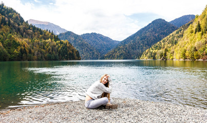 Girl in a gray tracksuit on the background of lake Ritsa in Abkhazia in autumn