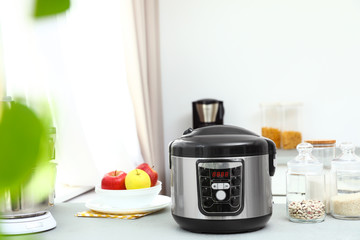 New modern multi cooker and products on table in kitchen. Space for text