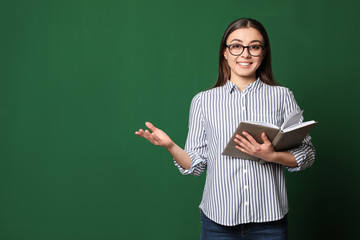 Portrait of young teacher with book on green background. Space for text