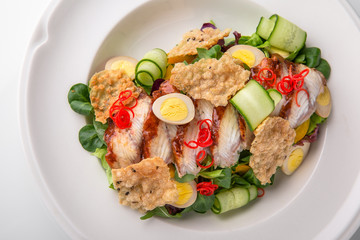 Delicious salad of smoked eel, fresh vegetables, quail eggs and crispy chips. Nutritious healthy dish. Banquet festive dishes. Gourmet restaurant menu. White background.