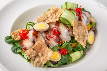 Delicious salad of smoked eel, fresh vegetables, quail eggs and crispy chips. Nutritious healthy dish. Banquet festive dishes. Gourmet restaurant menu. White background.