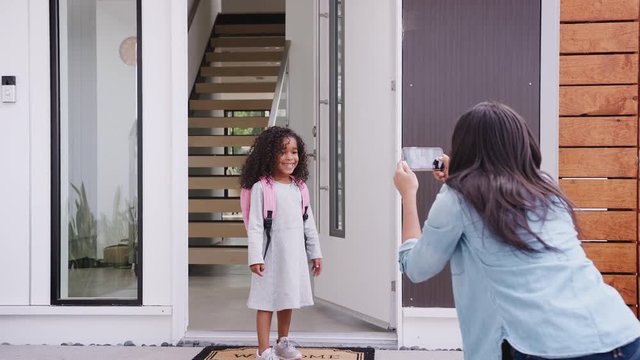 Mother Taking Photo Of Daughter With Cell Phone On First Day Back At School