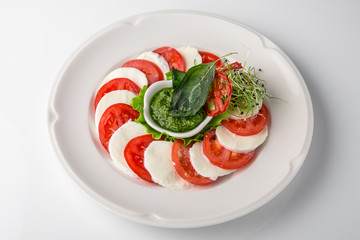 Traditional caprese of tomatoes, mozzarella and pesto sauce. Nutritious healthy dish. Banquet festive dishes. Gourmet restaurant menu. White background.