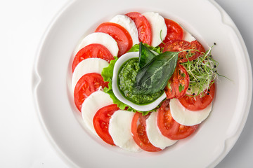 Traditional caprese of tomatoes, mozzarella and pesto sauce. Nutritious healthy dish. Banquet festive dishes. Gourmet restaurant menu. White background.