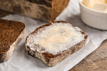 Fototapeta na wymiar Slice of rye bread with butter on wooden table, closeup