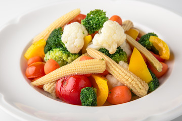 Fresh boiled vegetables: baby carrots, small corn dill, broccoli, cherry tomatoes, sweet peppers. Nutritious healthy dish. Banquet festive dishes. Gourmet restaurant menu. White background.