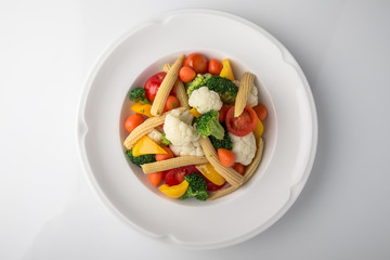 Fresh boiled vegetables: baby carrots, small corn dill, broccoli, cherry tomatoes, sweet peppers. Nutritious healthy dish. Banquet festive dishes. Gourmet restaurant menu. White background.