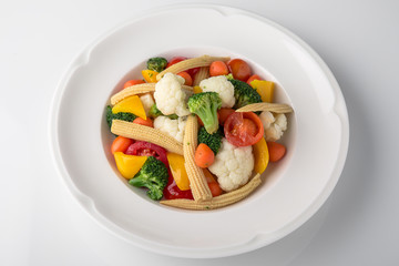 Fresh boiled vegetables: baby carrots, small corn dill, broccoli, cherry tomatoes, sweet peppers. Nutritious healthy dish. Banquet festive dishes. Gourmet restaurant menu. White background.