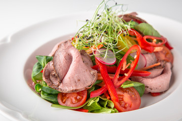 Salad of ham, prosciutto, pork or beef with vegetables, greens, berries and sauce. Nutritious, healthy dish. Banquet festive dishes. Gourmet restaurant menu. White background.