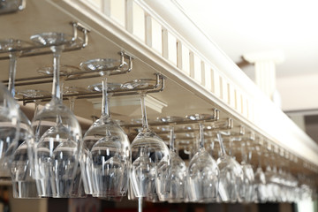Set of empty clean glasses on bar racks