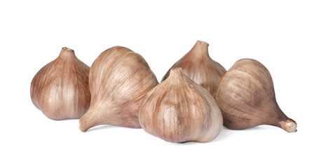 Unpeeled bulbs of black garlic on white background