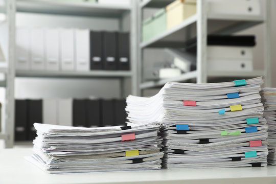 Stacks of documents with paper clips on office desk