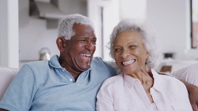 Portrait Of Loving Senior Couple Sitting On Sofa At Home Laughing Together