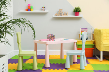 Stylish playroom interior with table, chairs and sofa