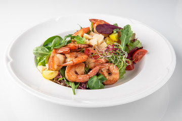 Luxurious seafood salad with grilled king prawns, fish, parmesan cheese, greens and vegetables. Banquet festive dishes. Fine dining restaurant menu. White background.