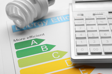 Energy efficiency rating chart, fluorescent light bulb and calculator, closeup