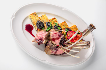 Rack of lamb (ribs) with berry sauce with prunes and quiche of broccoli, cheese and tomato. Banquet festive dishes. Fine dining restaurant menu. White background.