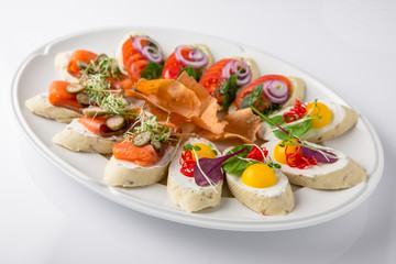 Bruschetta with salmon, avocado, capers, cucumber, radish, sweet pepper and cherry tomatoes. Banquet festive dishes. Fine dining restaurant menu. White background.