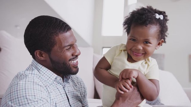 Father Playing With Baby Daughter Tickling Her At Home