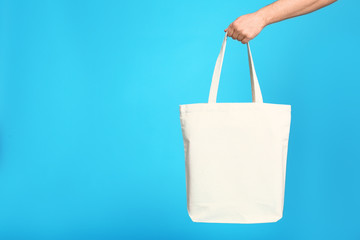 Young man with eco bag on blue background, closeup. Space for text