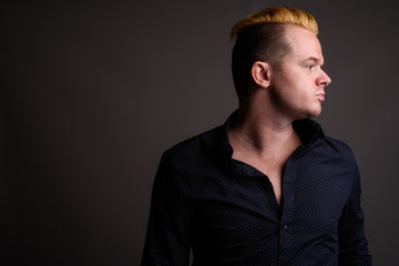 Businessman with Mohawk hairstyle and blond hair against gray ba