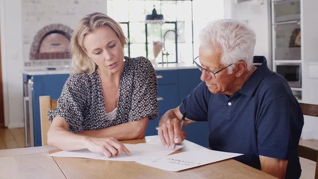 Woman Helping Senior Man To Complete Last Will And Testament At Home
